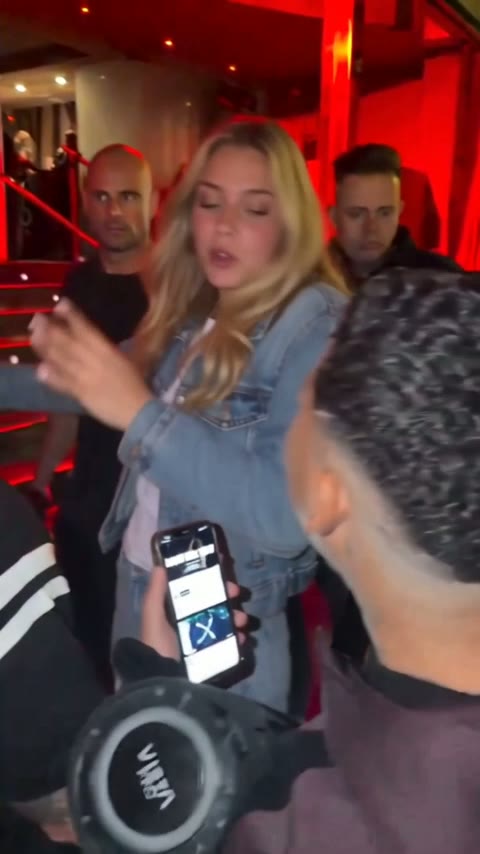Rapero inclinado hacia la pantalla de un teléfono, moviendo las dos manos