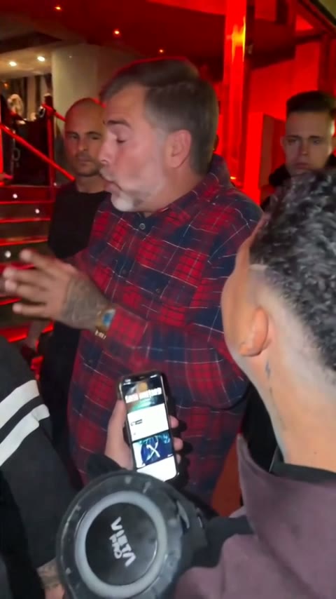 Dad with salt-and-pepper hair in a flannel shirt rapping under the red entrance light