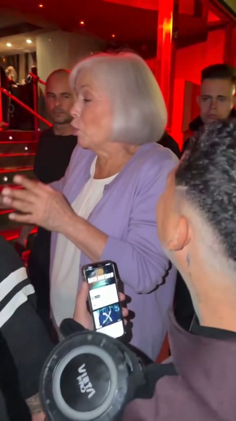 Grandmother around seventy with short white hair rapping at Kevin's phone